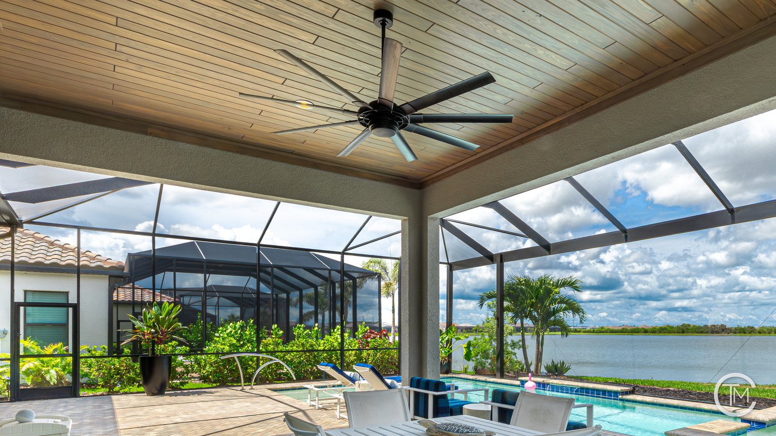 Outdoor kitchen under a wood plank lanai ceiling with recessed lights, a ceiling fan and bar-height dining