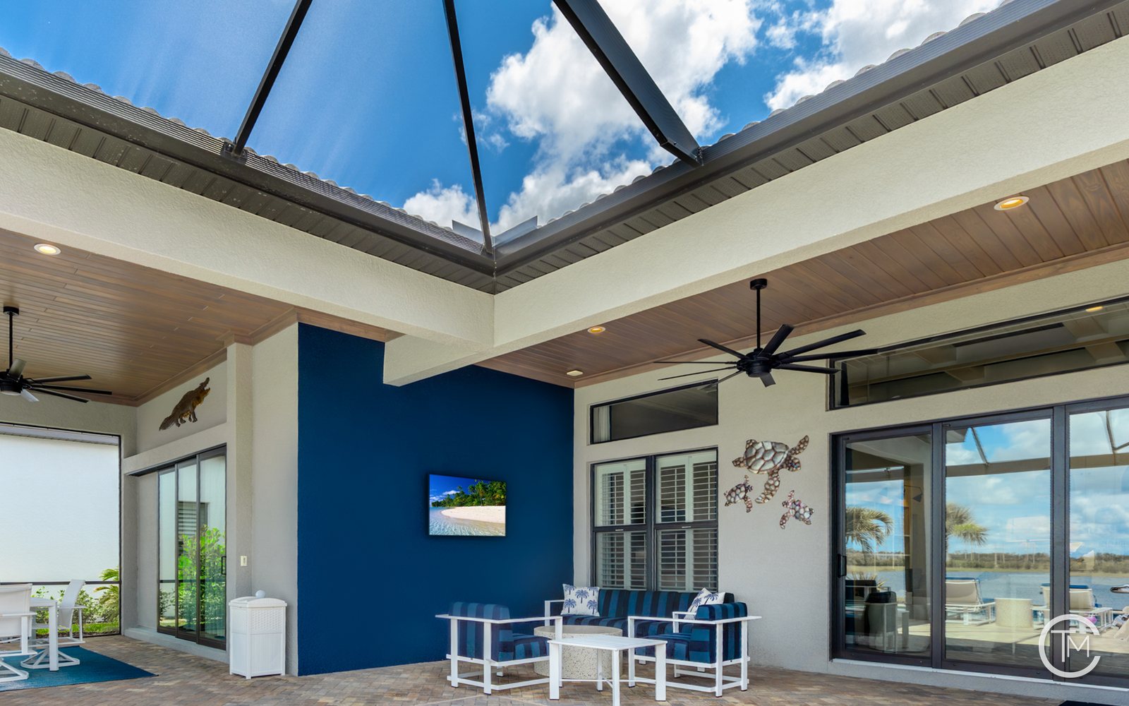Screened lanai with a stained wood plank ceiling, a large black ceiling fan and a pool and lake view